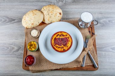 Kimyon, zeytin yağı ve pastirma ile nohut sarısı humus, tereyağı, gri arka planda seramik koyu kâsede servis edilir. Geleneksel Arap yemekleri. Vejetaryen sağlıklı akşam yemeği..