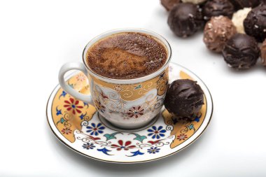 Beyaz arka planda çikolata şekerli bir fincan Türk kahvesi.