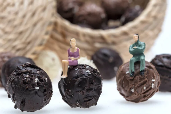chocolate truffles with miniature figurines on white background