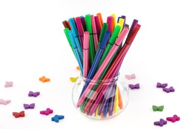 colorful felt pens in a glass jar on a white background