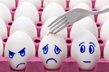 Komik yumurtalar, beyaz arka planda tüyleri olan bir kutuda yüz yumurtaları. Çizgi film kavramları, çocuklar için gıda dekorasyonu.