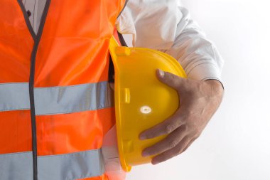 worker in protective gloves and helmet holding a yellow safety vest.