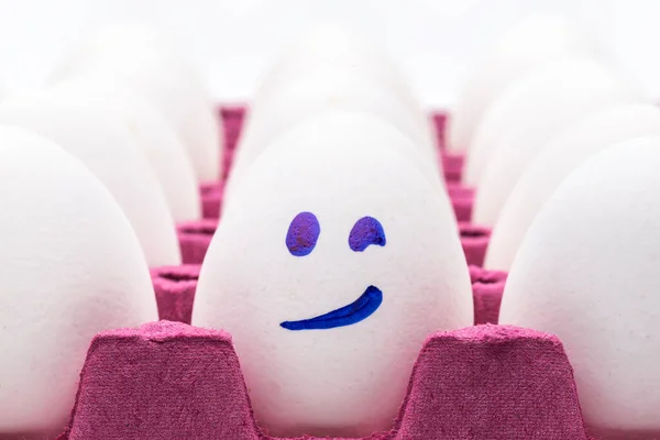 Funny eggs. One happy smiling egg amongst sad, angry and envious crowd of eggs isolated on white background