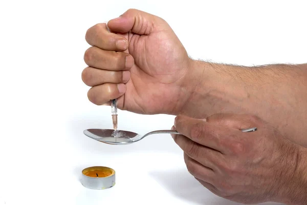 hand holding a spoon with a fork and a cigarette