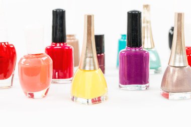 Beyaz arka planda duran ojeli çok renkli şişeler.