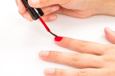 Kırmızı manikürlü güzel kadın elleri ve fırçalı tırnak cilası şişesi