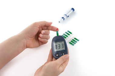 Glukometreyle yüksek kan şekerini ölçen Kadın Elleri 'nin yakın çekimi. İnsülin için glukometre ve şırınga, beyaz arka planda izole edilmiş diyabet mellitus izleme.