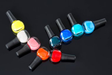 Güzel parlak renklerden oluşan tırnak cilası çeşitleri. Tırnak sanatı ve manikür konsepti. Renkli cilalı ya da ojeli. Yansıması olan siyah bir arkaplanda izole edilmiş.