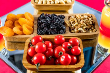 different types of food, dried fruits and nuts, and fresh red tomatoes on wooden background
