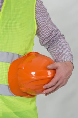 Mühendislik yönetimi inşaatı, mühendis güvenlik miğferi, işçi güvenliği için çalışma alanı arka planında. Busine konsepti. Gri arkaplanda kopyalama alanı olan miğfer tutan inşaat işçisi