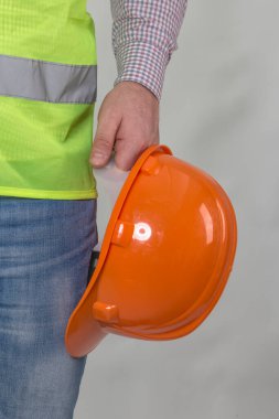 Mühendislik yönetimi inşaatı, mühendis güvenlik miğferi, işçi güvenliği için çalışma alanı arka planında. Busine konsepti. Gri arkaplanda kopyalama alanı olan miğfer tutan inşaat işçisi