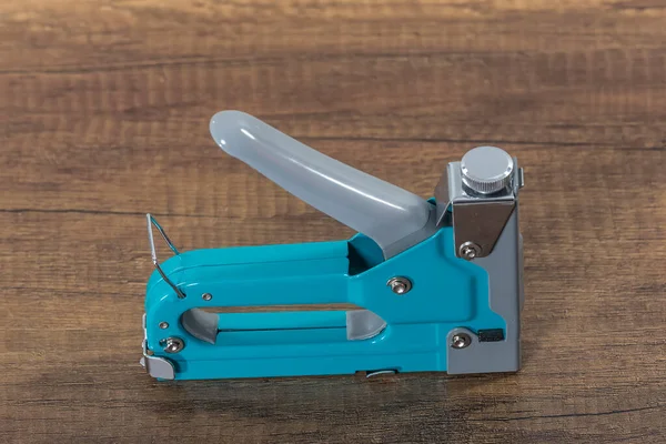 Metal furniture stapler. Staple gun. Construction staple on wooden board. Top view