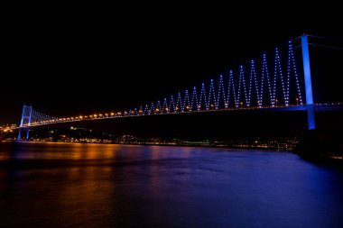 Geceleyin denizin üzerindeki Boğaz Köprüsü