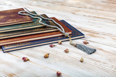 Kutsal Kur 'an' ın Arapça el yazısı ve ahşap masa üzerindeki tespih anlamına gelir. Seçici odak ve kırpma parçası.