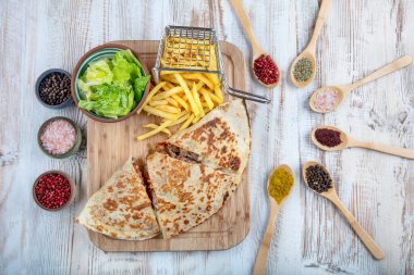 Kapalı pizza, sebzeli patates kızartması ve ahşap arka planda sos.