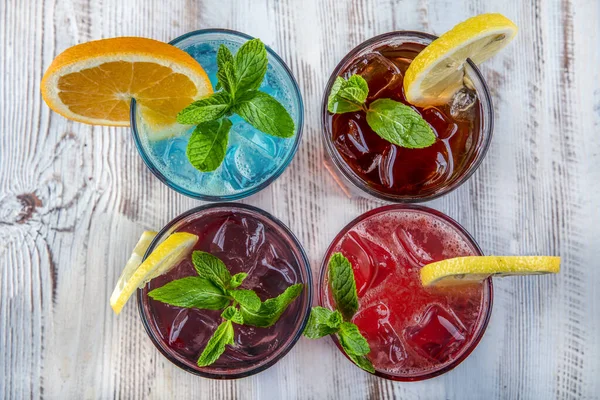 On a wooden table; Blue Hawaiian, Ice Tea, Strawberry Mojito and Forest Fruity Iced Drink.