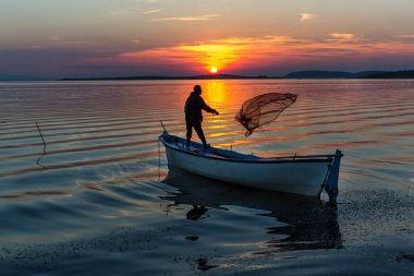beautiful sunrise over the lake with the silhouette of fishers on the boat