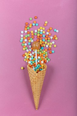 Renkli lolipopları ve pembe arka planda şekerlemeleri olan gözleme boynuzu. Top view, tatlılar ve şeker konsepti.