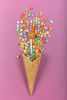 Renkli lolipopları ve pembe arka planda şekerlemeleri olan gözleme boynuzu. Top view, tatlılar ve şeker konsepti.