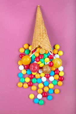 Renkli şekerli dondurma külahları, tatlı jölesi, çubukta lolipop, pembe arka planda çok renkli şekerlerin serpilmesi. Üst Manzara 'da dümdüz yatıyordu. Boşluğu kopyala.