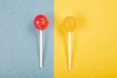 Renkli arkaplanda lolipop şekerlemeleri üst görünümde ve ortada bir lolipop var..