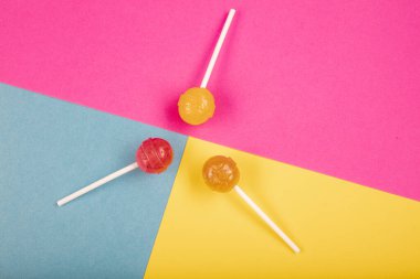 Renkli arkaplanda lolipop şekerlemeleri üst görünümde ve ortada bir lolipop var..