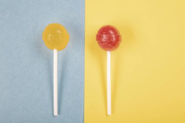Renkli arkaplanda lolipop şekerlemeleri üst görünümde ve ortada bir lolipop var..