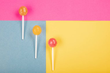 Renkli arkaplanda lolipop şekerlemeleri üst görünümde ve ortada bir lolipop var..