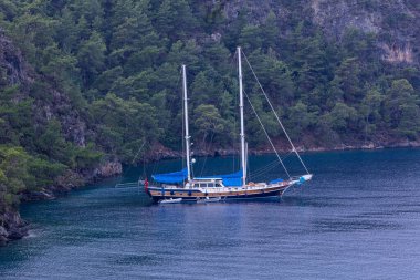 Akdeniz 'in Fethiye Körfezi' ndeki Oludeniz Koyu 'nda Türkiye' nin Mugla ilçesinin Fethiye ilçesindeki bir dağ sırasının zeminine demirlemiş klasik bir ahşap zevk yatı..