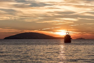 Gün batımında ufukta süzülen bir teknenin görüntüsü