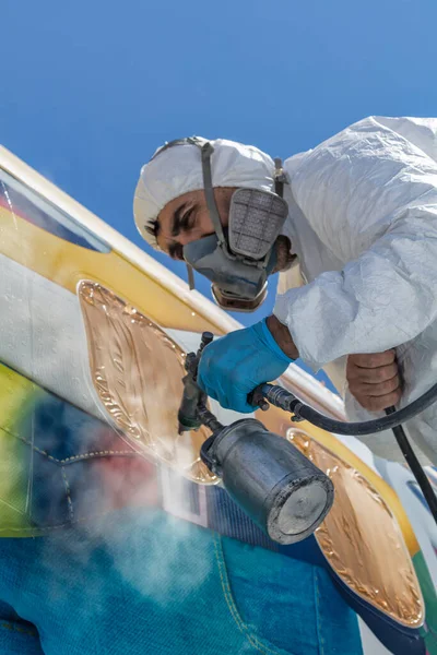 Aircraft painting and sandblasting. Spray painting, airplane wing. Worker in coverall using airbrush.