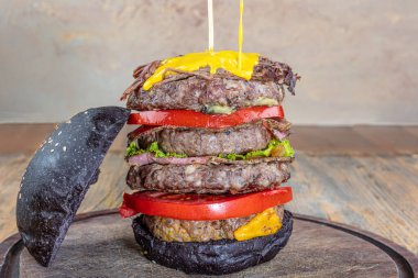 Erimiş peynirli büyük bir çizburger. Lezzetli iştah açıcı, sağlıklı vejetaryen siyah burgerler ahşap masada. Kopya uzayı ile yatay. Sağlıklı yemek kavramı, temiz yemek..