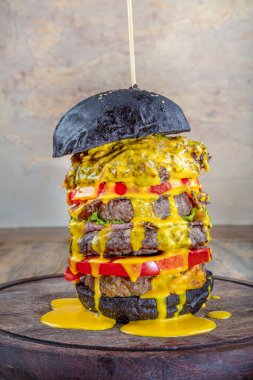 Erimiş peynirli büyük bir çizburger. Lezzetli iştah açıcı, sağlıklı vejetaryen siyah burgerler ahşap masada. Kopya uzayı ile yatay. Sağlıklı yemek kavramı, temiz yemek..