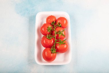 Yuvarlak domateslerle dolu beyaz bir kap. Organik sebzeler, marketteki kabinde domatesler..