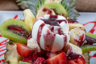 Çilekli, muzlu ve kivili bir top dondurmayla ananas ikiye bölünmüş. Tatlı diyeti için mükemmel ya da sağlıklı bir yemek için. Sağlıklı çiğ yiyecekler için aşk.