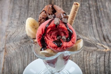 Vanilya, çilek ve çikolatalı dondurma. Dondurmalı gofret çubuğu ya da ahşap zeminde izole edilmiş cam..