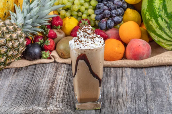 Cold coffee drink frappe (frappuccino), with whipped cream and caramel syrup, with straws and grains of coffee on a wooden table, copy space.