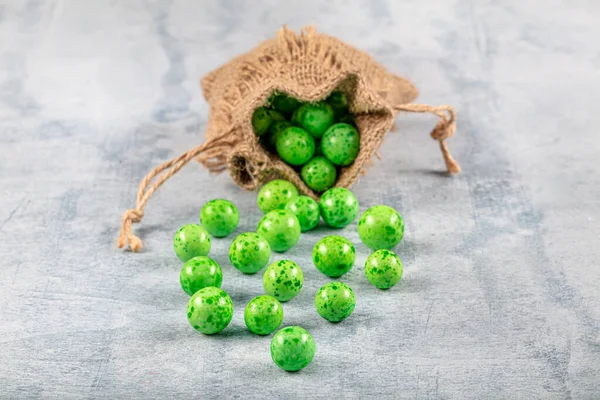 Green Candy Chickpeas; Roasted chickpeas covered in chocolate, fruit sauce in linen sack on wooden background.