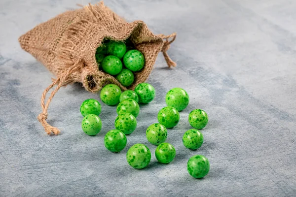 Green Candy Chickpeas; Roasted chickpeas covered in chocolate, fruit sauce in linen sack on wooden background.