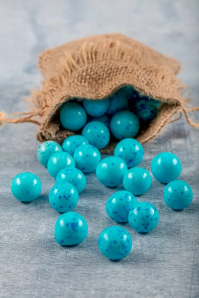 Blue Candy Chickpeas; Roasted chickpeas covered in chocolate, fruit sauce in linen sack on wooden background.