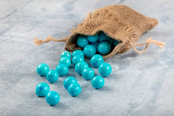 Blue Candy Chickpeas; Roasted chickpeas covered in chocolate, fruit sauce in linen sack on wooden background.