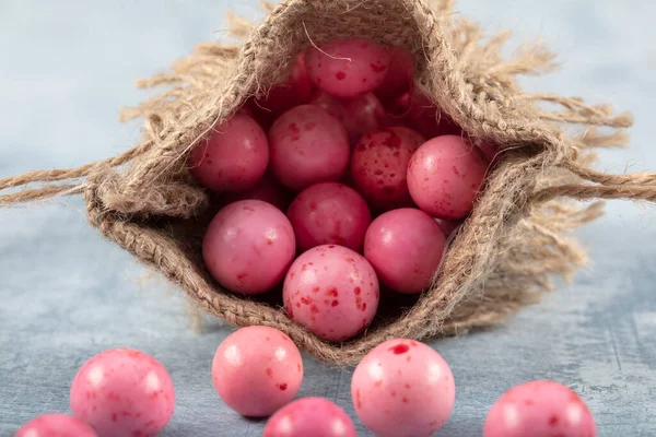 Pink Candy Chickpeas; Roasted chickpeas covered in chocolate, fruit sauce in linen sack on wooden background.