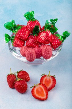 Çilek tatlısı ve çilek aromalı şeker konsepti. Tatlı ve ekşi kırmızı ekşi kemerlerle kaplı, ahşap bir arka planda izole edilmiş şeker..