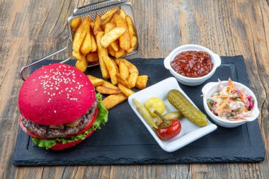 Kırmızı ekmek, hamburger. Amerikan biftekli hamburgerleri turşu, ketçap, mayonez ve kızarmış patates. Moda yemekler. Restoran menüsü kavramı.