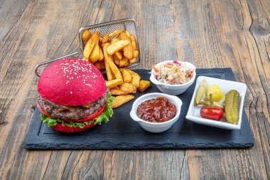 Kırmızı ekmek, hamburger. Amerikan biftekli hamburgerleri turşu, ketçap, mayonez ve kızarmış patates. Moda yemekler. Restoran menüsü kavramı.