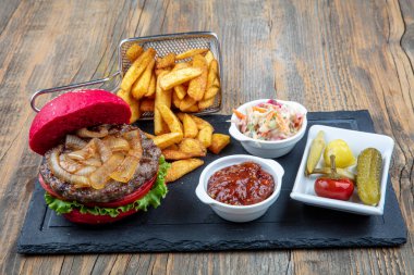 Kırmızı ekmek, hamburger. Amerikan biftekli hamburgerleri turşu, ketçap, mayonez ve kızarmış patates. Moda yemekler. Restoran menüsü kavramı.