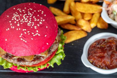 Kırmızı ekmek, hamburger. Amerikan biftekli hamburgerleri turşu, ketçap, mayonez ve kızarmış patates. Moda yemekler. Restoran menüsü kavramı.