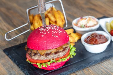 Kırmızı ekmek, hamburger. Amerikan biftekli hamburgerleri turşu, ketçap, mayonez ve kızarmış patates. Moda yemekler. Restoran menüsü kavramı.