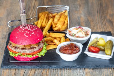 Kırmızı ekmek, hamburger. Amerikan biftekli hamburgerleri turşu, ketçap, mayonez ve kızarmış patates. Moda yemekler. Restoran menüsü kavramı.