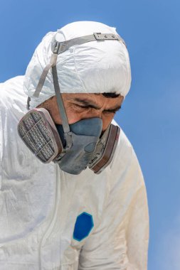 Uçak boyama ve kum püskürtme. Sprey boya, uçak kanadı. Hava fırçası kullanan örtülü bir işçi.